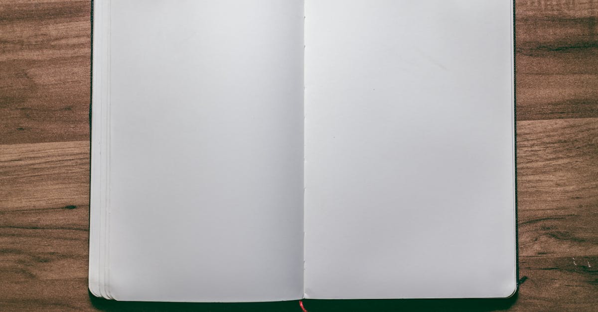 A top-down view of an open blank notebook on a wooden desk, perfect for design or writing projects.